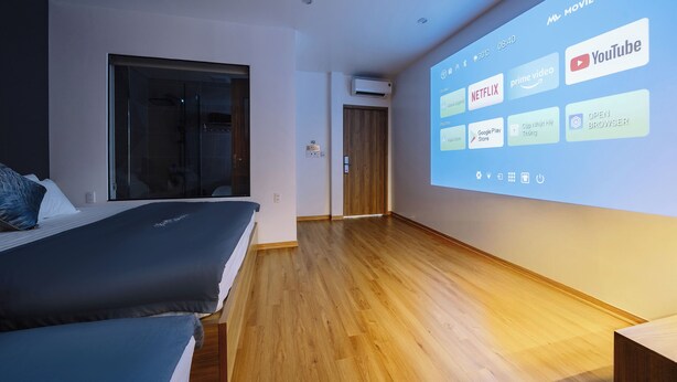 A hotel room with a bed, a shower, and a wall-mounted projector displaying streaming services. - Minn Cat Ba (Hai Phong)