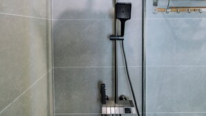 A shower with a black head, a control panel, and a towel rack. - Minn Cat Ba (Hai Phong)