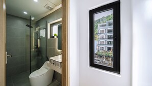 A modern bathroom with a glass-enclosed shower, a toilet, and a sink with a mirror above it. - Minn Cat Ba (Hai Phong)