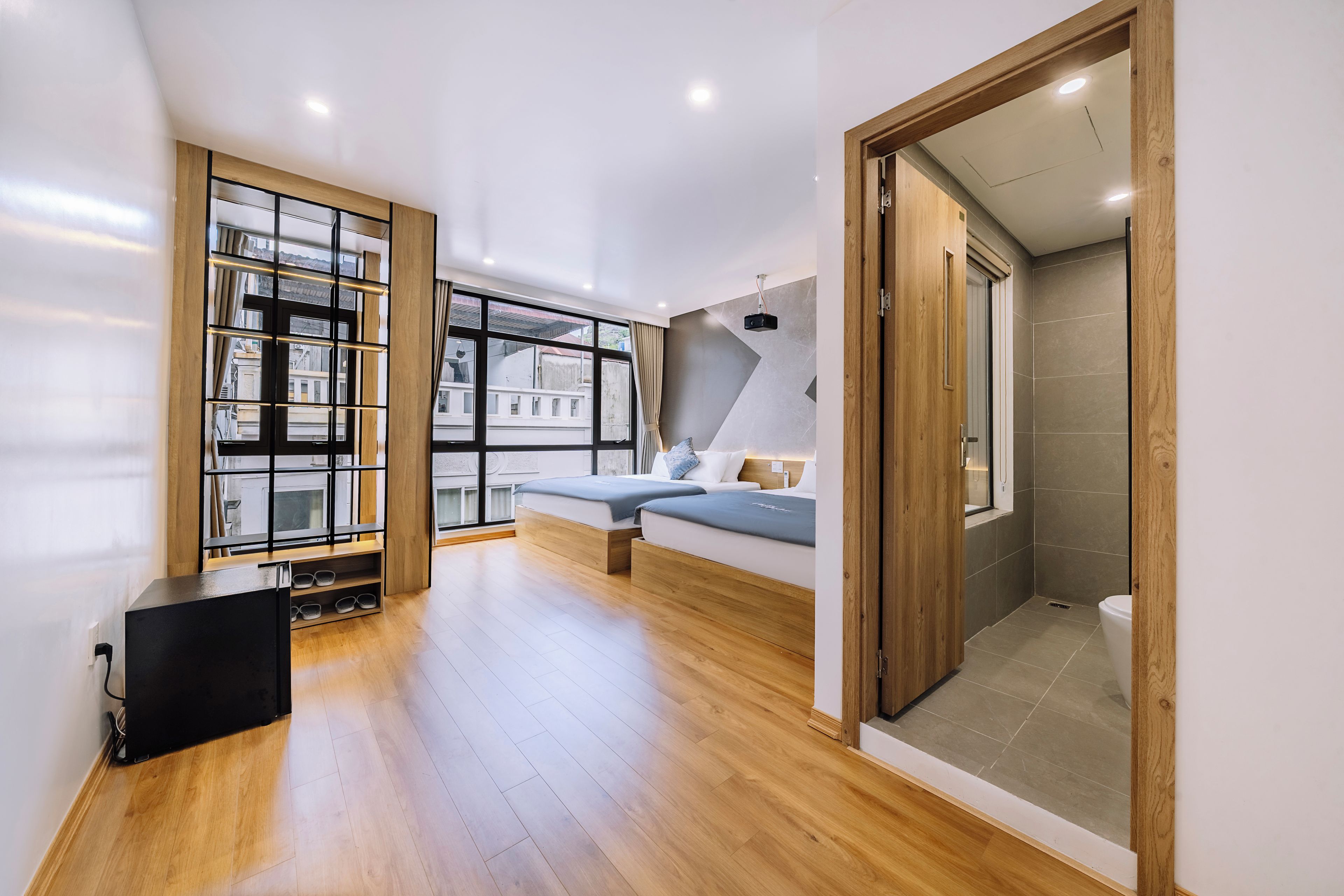 A modern hotel room with a large window, a built-in bench, and a shower area.
