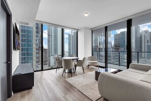 A modern living room with a dining area, large windows, and a city view. - Miami Pulse With Resort Amenities (Miami)