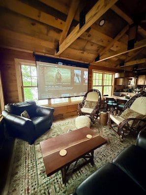 A cozy living room with a wooden ceiling, a large TV screen, comfortable seating, and a view of the outdoors. - Green Wolf Lodge-Peaceful, 3-Bedroom Cabin on Spider Lake Chain near Hayward (Hayward)
