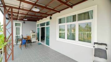A covered balcony with a table and chairs, a ceiling fan, and a view of a residential area.