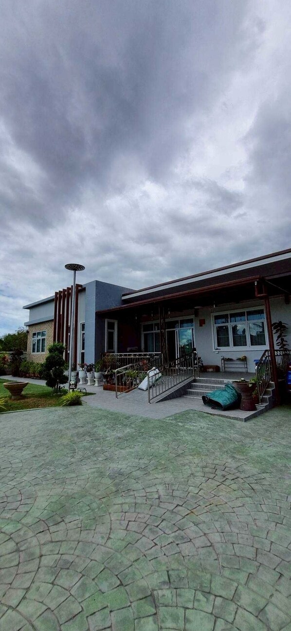 A building with a modern architectural style, featuring a flat roof, large windows, and a covered entrance with a staircase. - Mae Klong Garden House (Mueang Samut Songkhram District)