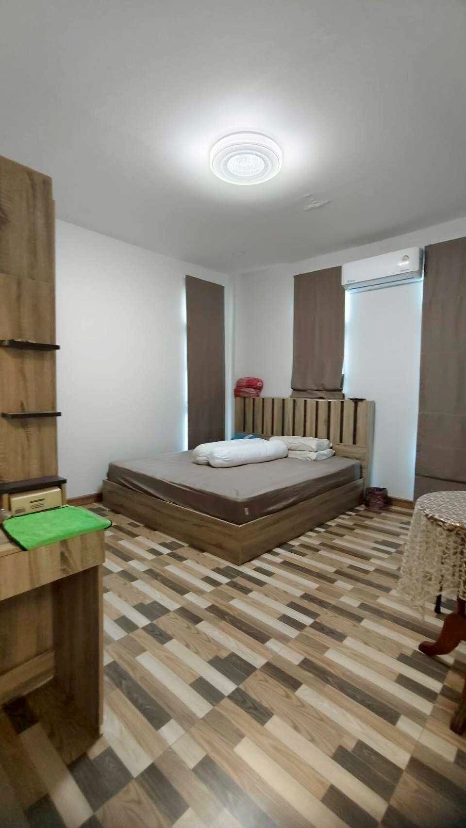 A bedroom with a bed, a desk, a chair, a window, and a ceiling light.