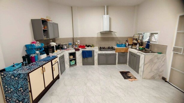 Una cocina con encimera de mármol, armarios grises, estufa a gas y horno empotrado.