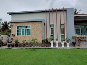A modern building with a flat roof, a large window, and a series of vertical columns. - Mae Klong Garden House (Mueang Samut Songkhram District)