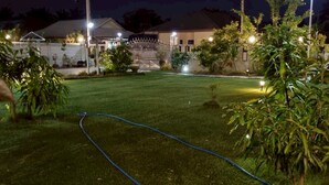 Un espacio exterior bien iluminado con césped, una reja de metal y diversas plantas.