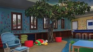 A children's playroom with a tree, colorful handprints on walls, and a blue carpet. - 1 Bedroom Villa at Lakeshore Reserve w/ Amenities (Orlando)