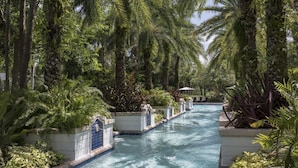 A swimming pool surrounded by lush greenery and palm trees. - 1 Bedroom Villa at Lakeshore Reserve w/ Amenities (Orlando)