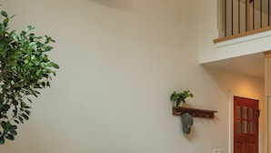 A living room with a brown sofa, two grey ottomans, a small white table with a candle, and a potted plant.