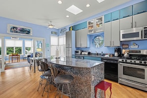 A modern kitchen with granite countertops, stainless steel appliances, and blue cabinetry. - Sleepy Hollow Beach Resort, Villa E – Family Fun on Lake Michigan! (South Haven)