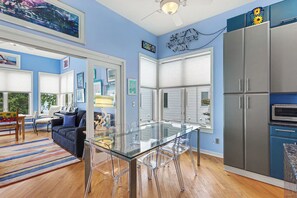 A modern kitchen with a glass dining table, stainless steel appliances, and a blue accent wall. - Sleepy Hollow Beach Resort, Villa E – Family Fun on Lake Michigan! (South Haven)