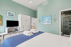A hotel room with a bed, a television, a wardrobe, and a shower area. - Sleepy Hollow Beach Resort, Villa E – Family Fun on Lake Michigan! (South Haven)