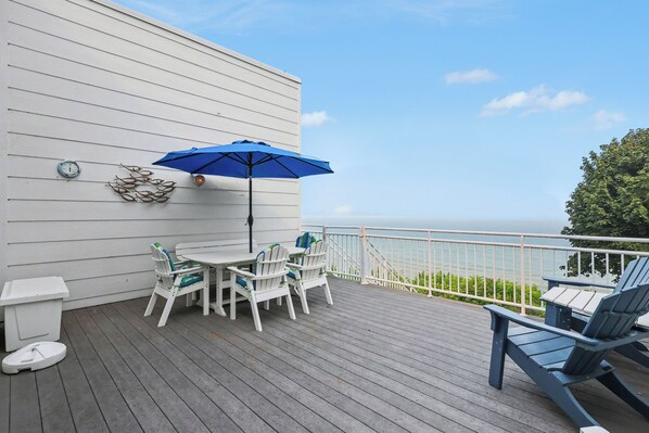 A deck with a table and chairs, a blue umbrella, and a view of the ocean. - Sleepy Hollow Beach Resort, Villa E – Family Fun on Lake Michigan! (South Haven)