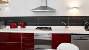 Eine moderne Küche mit Gasherd, Backofen, Geschirrspüler und einer roten und weißen Farbgestaltung.