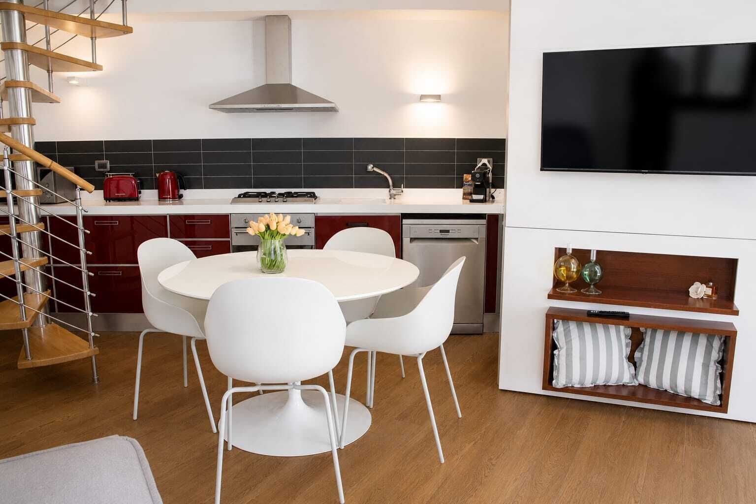 Una cucina moderna con zona pranzo, una scala e un televisore.