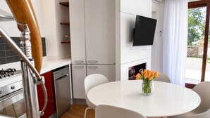 A modern kitchen with white cabinets, a built-in oven, and a dining area with a white table and chairs.