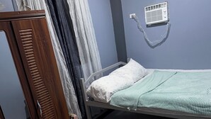 A room with a bed, a wardrobe, a radiator, and a colorful rug.