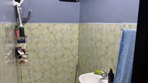 A bathroom with a toilet, sink, shower, and a blue towel hanging on the wall.