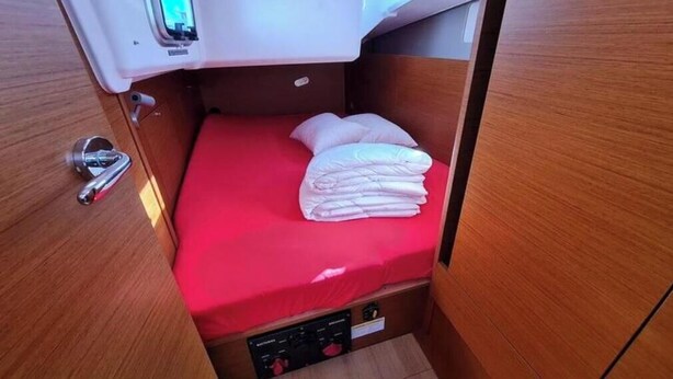 Ein gemütliches Kabinett mit einem Einzelbett, einer kleinen Bedienkonsole und einem Türgriff.