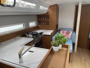 A compact galley with a sink, stove, and storage cabinets. - Sun Odyssey 410 - Rosso Bianco (Marina Veruda)