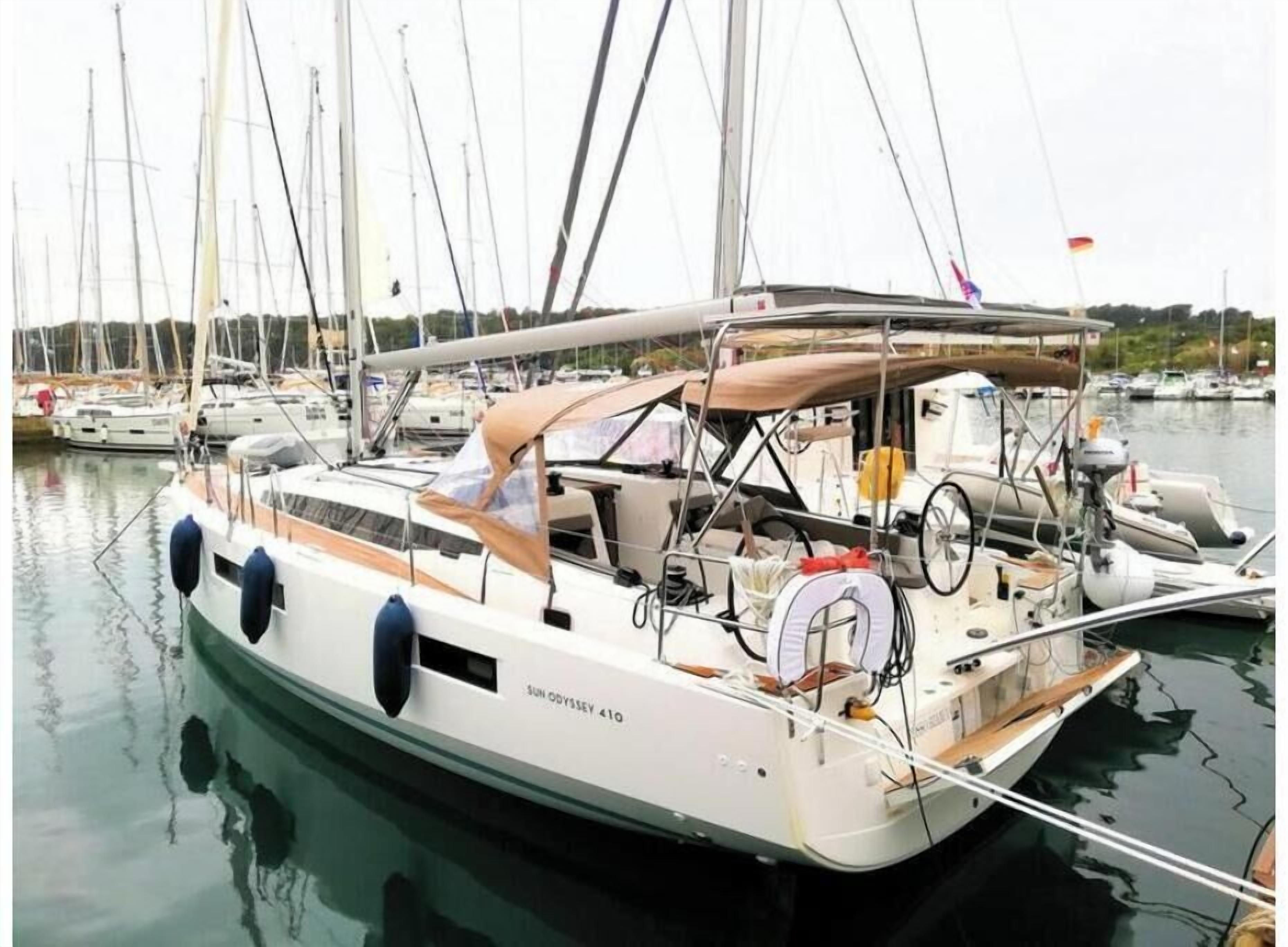 Eine Segelyacht liegt in einer Marina festgemacht, mit mehreren Masten und einem überdachten Deck.
