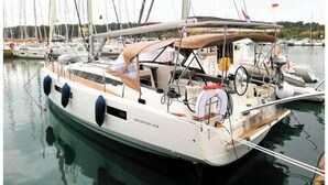 Eine Segelyacht liegt in einer Marina festgemacht, mit mehreren Masten und einem überdachten Deck.
