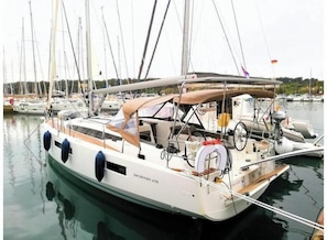 A sailboat docked at a marina with multiple masts and a covered deck area. - Sun Odyssey 410 - Rosso Bianco (Marina Veruda)