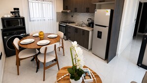Eine moderne Küche mit Essbereich, inklusive Kaffeemaschine, Mikrowelle und Kühlschrank.