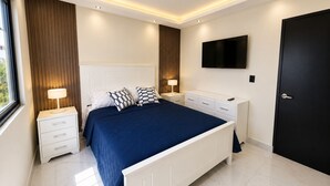 Ein modernes Schlafzimmer mit einem Bett, Nachttischen, einem Fernseher und einer Tür.