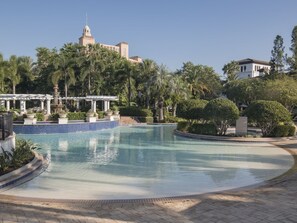 A swimming pool with a pavilion, palm trees, and a building with a dome in the background. - 3 Bedroom Villa at Lakeshore Reserve w/ Amenities (Orlando)
