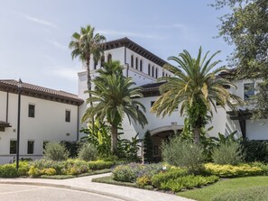 A white building with a tiled roof, surrounded by palm trees and well-maintained gardens. - 3 Bedroom Villa at Lakeshore Reserve w/ Amenities (Orlando)