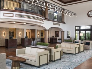 A spacious lobby with a reception desk, seating area, and a balcony with railings. - 3 Bedroom Villa at Lakeshore Reserve w/ Amenities (Orlando)