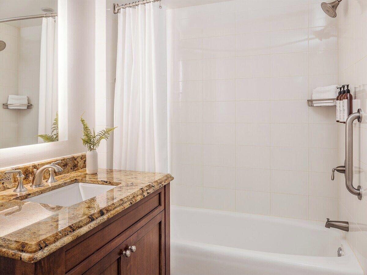 A bathroom with a sink, vanity, and bathtub.