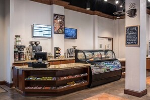 A coffee shop interior with a counter, espresso machine, menu boards, and a pastry display. - 3 Bedroom Villa at Lakeshore Reserve w/ Amenities (Orlando)