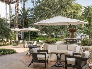 Une terrasse extérieure aménagée avec des meubles en osier, une table ronde et deux parasols.