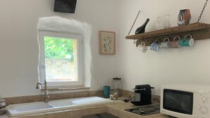 Et kompakt køkken med vask, mikrobølgeovn, køleskab og et vindue.