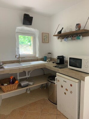 Eine kleine Küche mit Spüle, Mikrowelle, Kühlschrank und einem Fenster.