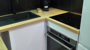 A compact kitchen with a black countertop, a built-in oven, and a dishwasher. - The Albino Oracle (Nîmes)