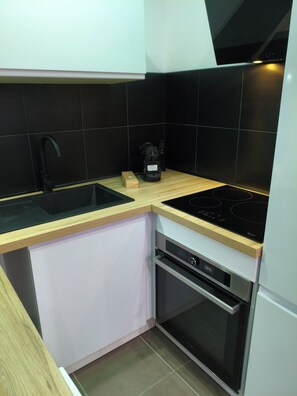 A compact kitchen with a black countertop, a built-in oven, and a dishwasher. - The Albino Oracle (Nîmes)