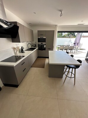 A modern kitchen with a built-in oven and microwave, a dining area with a large table and chairs, and a view of the outdoors. - Large, air-conditioned family home with a pool in Toulon, Var (La Valette-du-Var)