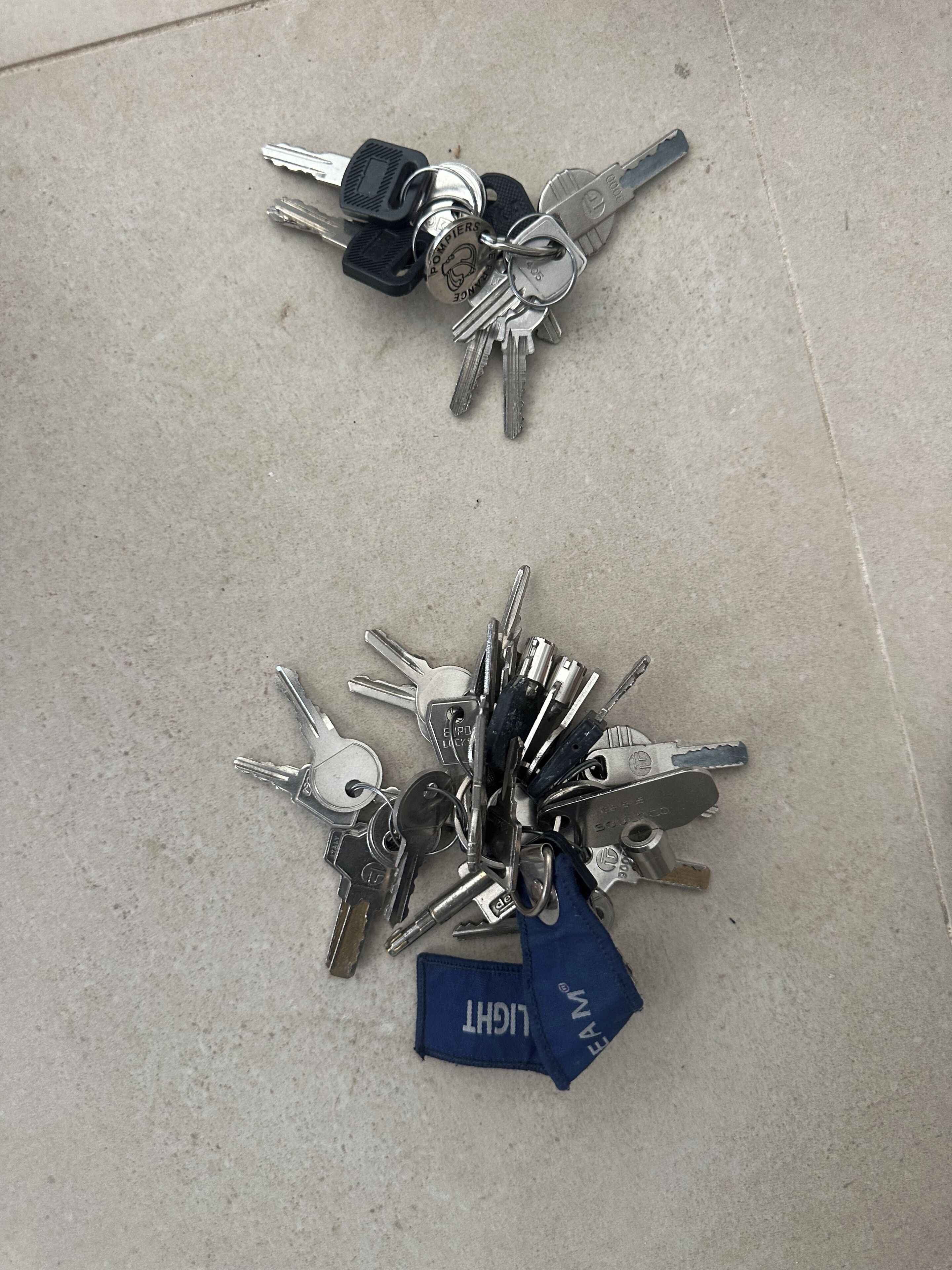 A collection of keys and a blue cloth on a concrete floor.