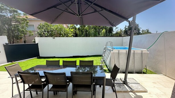 En uteplats med ett bord och stolar, en pool och ett takförsett område.