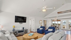 A spacious living room with grey sofas, a wooden coffee table, a flat-screen TV, and a ceiling fan. - Making Memories: Oceanfront 6 BR | Hot Tub | Shared Pool (Duck)
