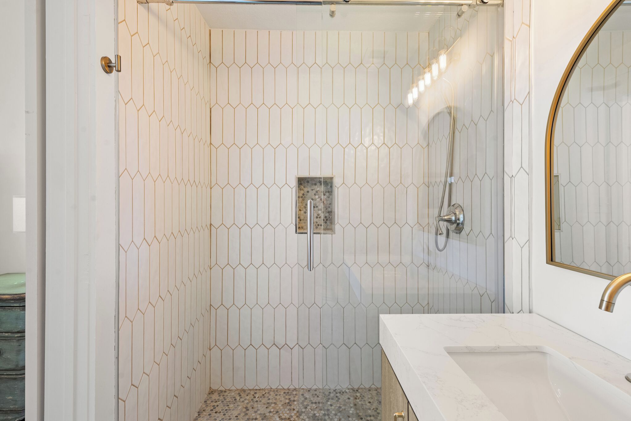 A bathroom with a shower, a sink, and a mirror.