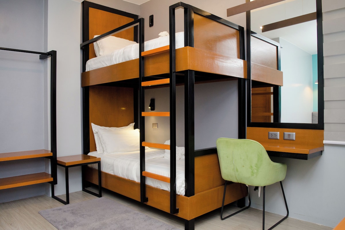 A bunk bed with a desk and chair, a mirror, and a light switch on the wall.