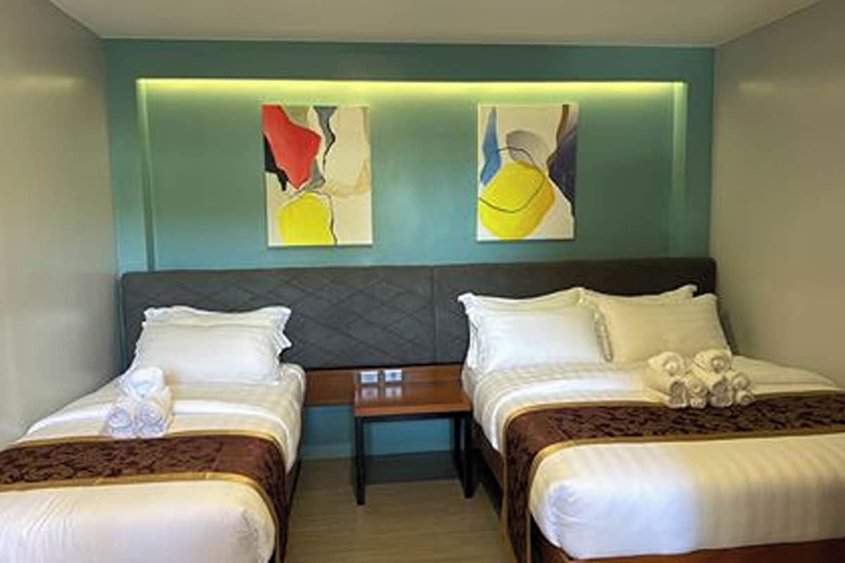 A hotel room with two beds, a nightstand, and abstract wall art.