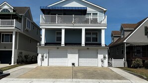 Una casa residenziale a due piani con garage anteriore, un balcone e vialetto.