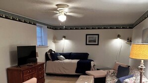 Una camera da letto con un letto, una cassettiera, una televisione, una ventola a soffitto e una lampada.
